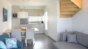 A modern kitchen with a dining area, a grey sofa, and a staircase with a wooden finish. - Modern Holiday Home, Near the Sea (Bredene)