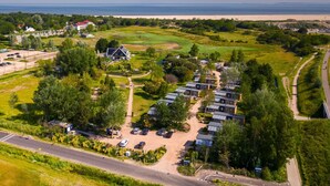 Vista aérea de una zona residencial con varias casas, un campo de golf y una playa al fondo.