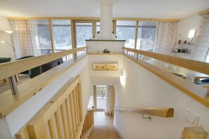 A multi-level interior with wooden railings, a staircase, and a view through the windows.