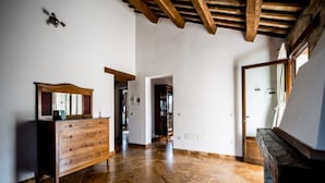 A spacious room with a wooden dresser, a stone floor, and a high ceiling with exposed beams. - Serene Escape, Ascoli Piceno (Ripatransone)