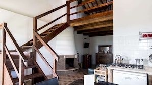 A rustic kitchen with a wooden staircase, a brick fireplace, and a gas stove. - Belvilla by Oyo Giglio (Ripatransone)