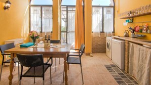 A bright room with a dining table, chairs, a kitchen area, and large windows with curtains. - Beautiful Apartment in Ascoli Piceno with Hot Tub (Ripatransone)
