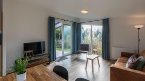 Una sala de estar moderna con televisor de pantalla plana, muebles de madera, un sofá y una mesa de comedor.