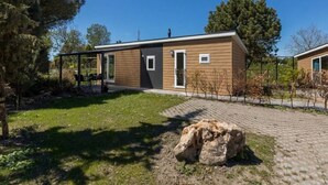 A modern single-story house with a wooden exterior, a small front porch, and a paved driveway. - Cozy Chalet at Holiday Park Fort den Haak (Vrouwenpolder)