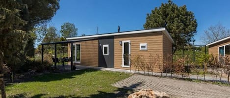 A modern single-story house with a wooden exterior, a small front porch, and a paved driveway.