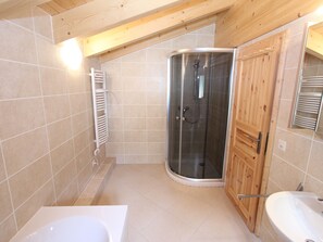 Un baño moderno con cabina de ducha de vidrio, tocador de madera y bañera.