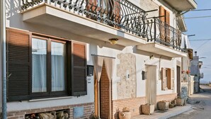 Un bâtiment à deux étages doté d’un balcon, d’une cheminée et d’un mur en pierre.
