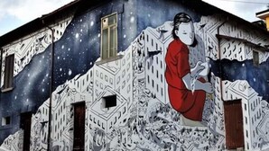 Une fresque représentant une personne sur un bâtiment, avec un motif abstrait et complexe.