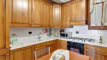 A kitchen with wooden cabinets, a microwave, stove, sink, and a table with a decorative bowl.