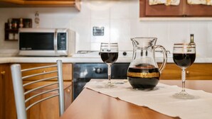 Une cuisine avec des meubles en bois, un four à micro-ondes, une cuisinière et une table sur laquelle sont posés deux verres à vin et une carafe.