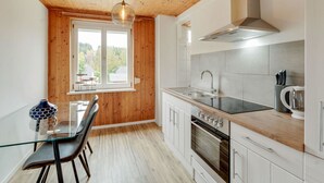 Une cuisine moderne avec un plafond en bois, une table à manger avec des chaises, une grande fenêtre et des appareils électroménagers en acier inoxydable.