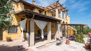 A yellow building with a covered patio area, outdoor seating, and a pergola. - Apartment in Ascoli Near Mountains (Ripatransone)