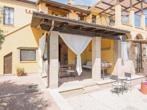 A yellow building with a covered patio area featuring a table and chairs. - Apartment in Ascoli Near Mountains (Ripatransone)