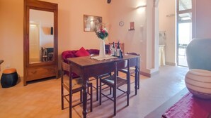 A dining area with a wooden table and chairs, a red sofa, a vase with flowers, and a clock on the wall. - Apartment in Ascoli Near Mountains (Ripatransone)