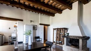 A dining area with a wooden table and chairs, a fireplace, and a kitchen in the background. - Lovely Apartment in Ascoli Piceno with Hot Tub (Ripatransone)