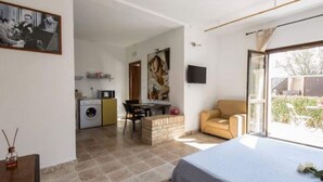 A bedroom with a bed, a sofa, a TV, a painting, and a kitchen area in the background. - Apartment in Ascoli Near Sea Beach (Ripatransone)