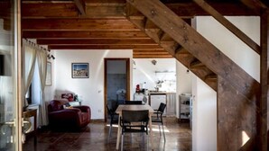 A rustic interior with a wooden staircase, a dining area with a table and chairs, and a kitchen in the background. - Serene Apartment in Ascoli Piceno with Hot Tub (Ripatransone)