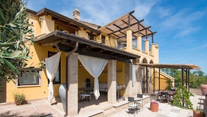 A yellow building with a covered patio area, outdoor seating, and a pergola. - Serene Apartment in Ascoli Piceno with Hot Tub (Ripatransone)