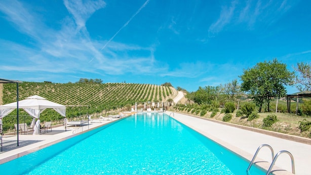 A swimming pool with a clear blue water, surrounded by a white canopy and lounge chairs. - Serene Apartment in Ascoli Piceno with Hot Tub (Ripatransone)
