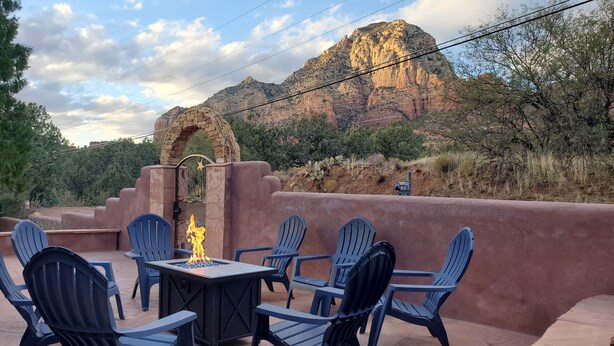 Un espace extérieur aménagé avec des chaises et une table, un foyer et une vue sur une montagne.