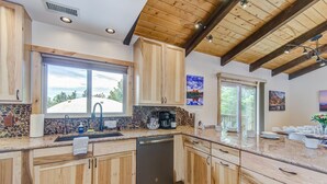 Une cuisine avec des meubles en bois, un pare-feu en pierre et une vue sur un paysage enneigé par la fenêtre.