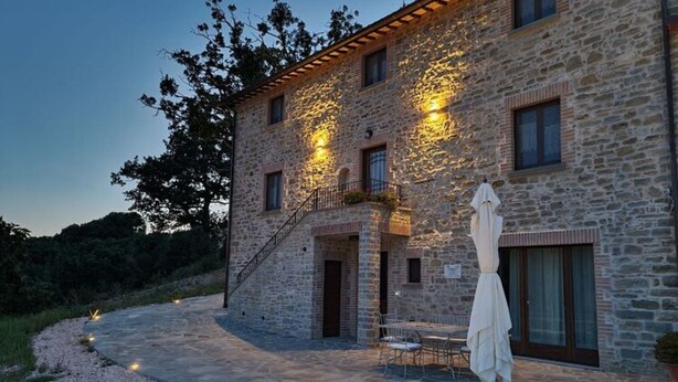 A stone building with a staircase, outdoor seating, and a statue.