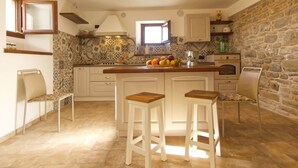 A kitchen with a stone wall, a tiled backsplash, and a fruit bowl on the counter.
