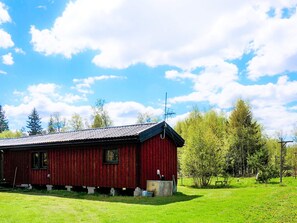 A red wooden building with a metal roof, situated in a grassy area with trees in the background. - 4 Person Holiday Home in Sandhem (Sandhem)