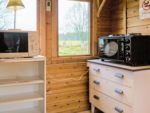 Enjoy a homey kitchen with a view of the surrounding grassy field, featuring a convenient cabinet and microwave.