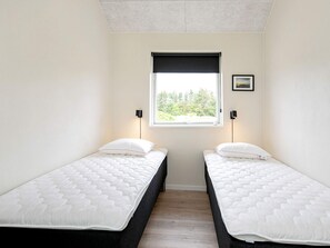 A room with two single beds, a window with a view of greenery, and two wall-mounted lamps. - Holiday Home in Thisted (Thisted)