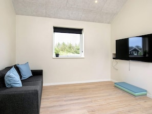 A room with a sofa, a window, a flat-screen TV, and a wooden floor. - Holiday Home in Thisted (Thisted)