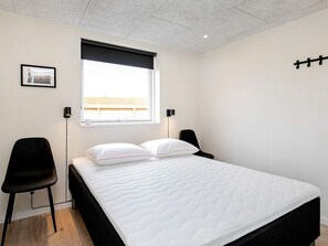 A bedroom with a bed, two chairs, a window with a view, and a picture on the wall. - Holiday Home in Thisted (Thisted)