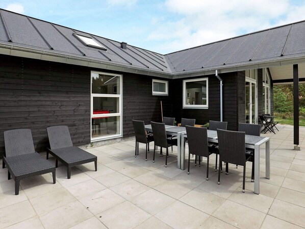 An outdoor patio area with a table and chairs, a covered seating area, and a view of the surrounding landscape.