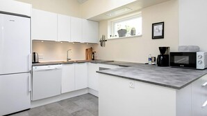 Una cucina moderna con mobili bianchi, lavastoviglie integrata, forno a microonde e macchina del caffè.