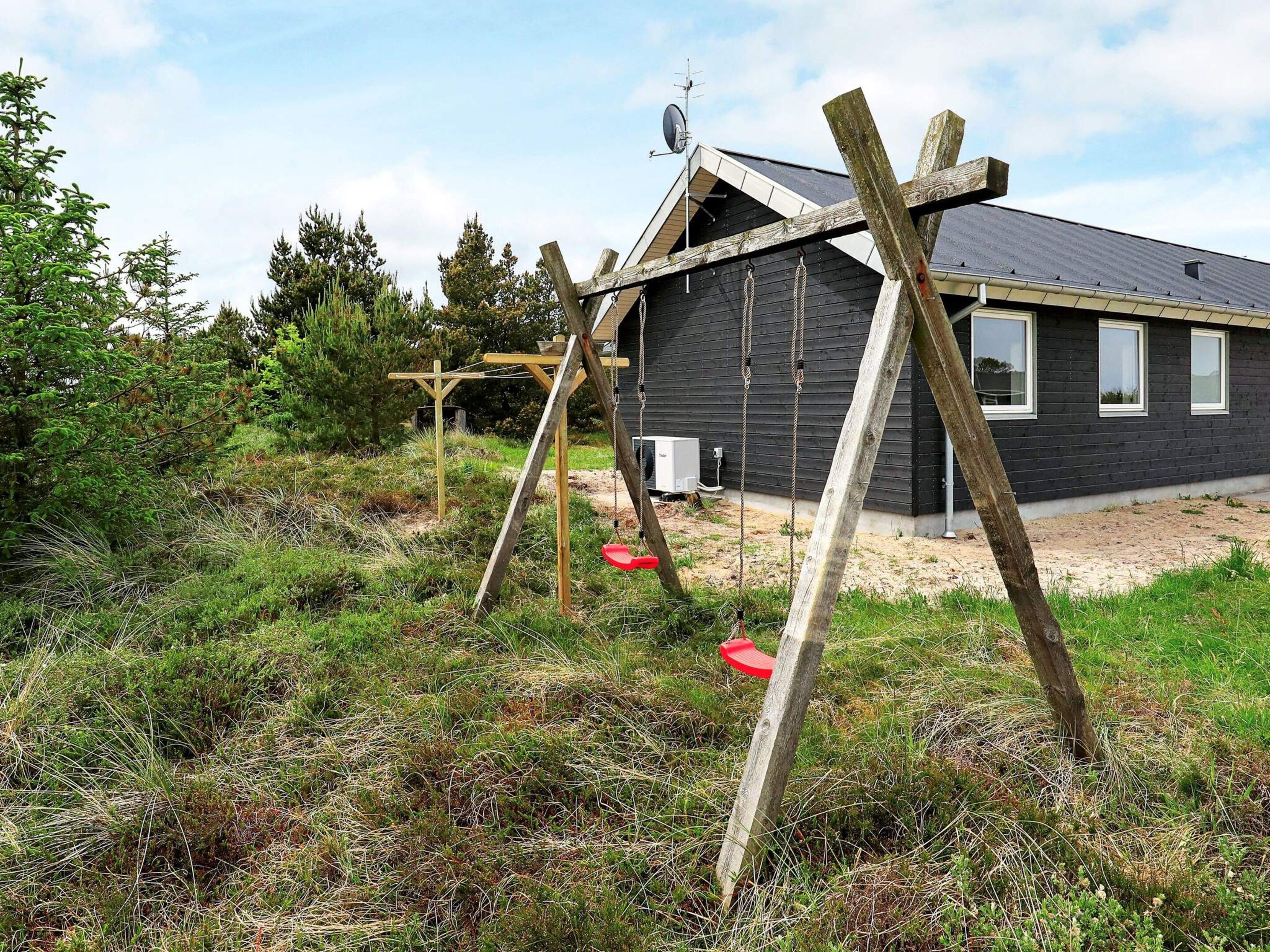 A house with a dark exterior, a satellite dish, and a swing set in the yard.