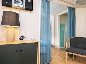 A room with a wooden cabinet, a lamp, a decorative item, and a chair.