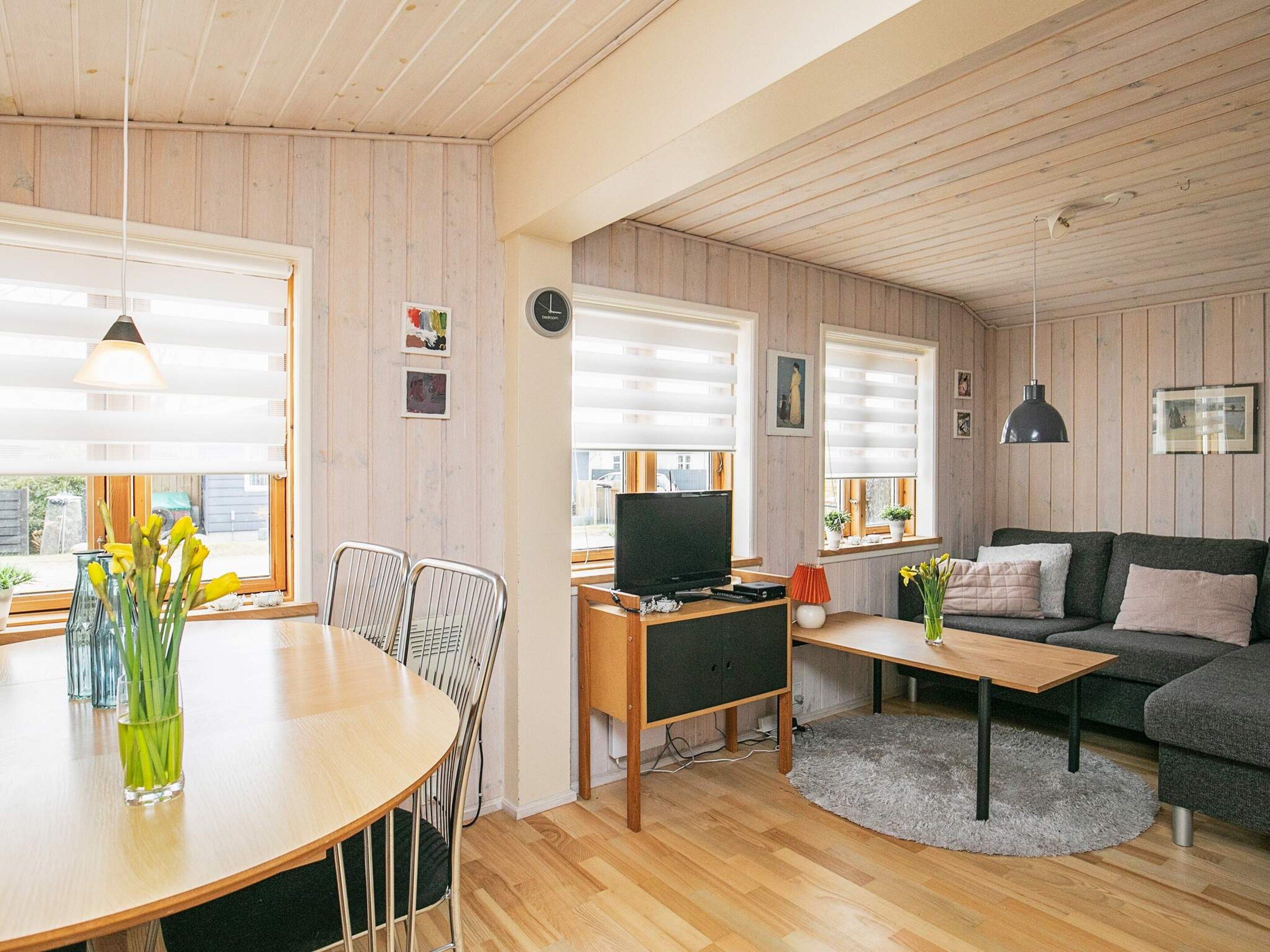 A modern living space with a dining area, a sofa, and a television.