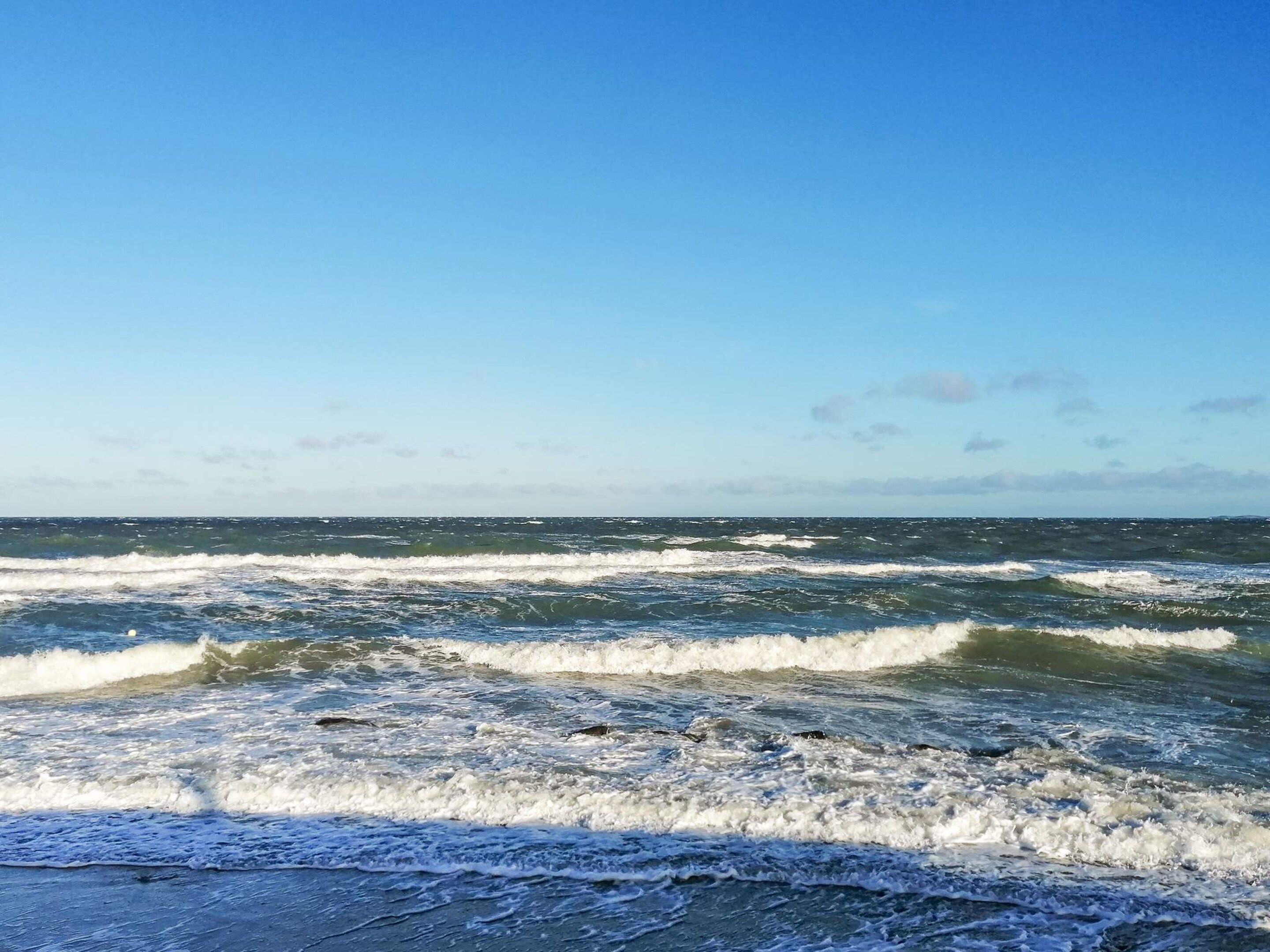A beach with waves and a clear sky.