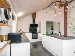 A modern kitchen with a central island, built-in appliances, and a hanging light fixture.