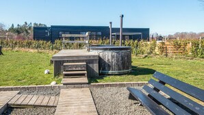 A modern building with a wooden deck, a large cylindrical structure, and a bench. - Holiday Home in Glesborg (Glesborg)