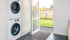 A laundry room with two Samsung washing machines and a glass door leading to a grassy outdoor area. - Holiday Home in Glesborg (Glesborg)