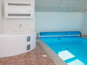 A swimming pool with a blue liner, a white jacuzzi, and a ceiling with a textured pattern.