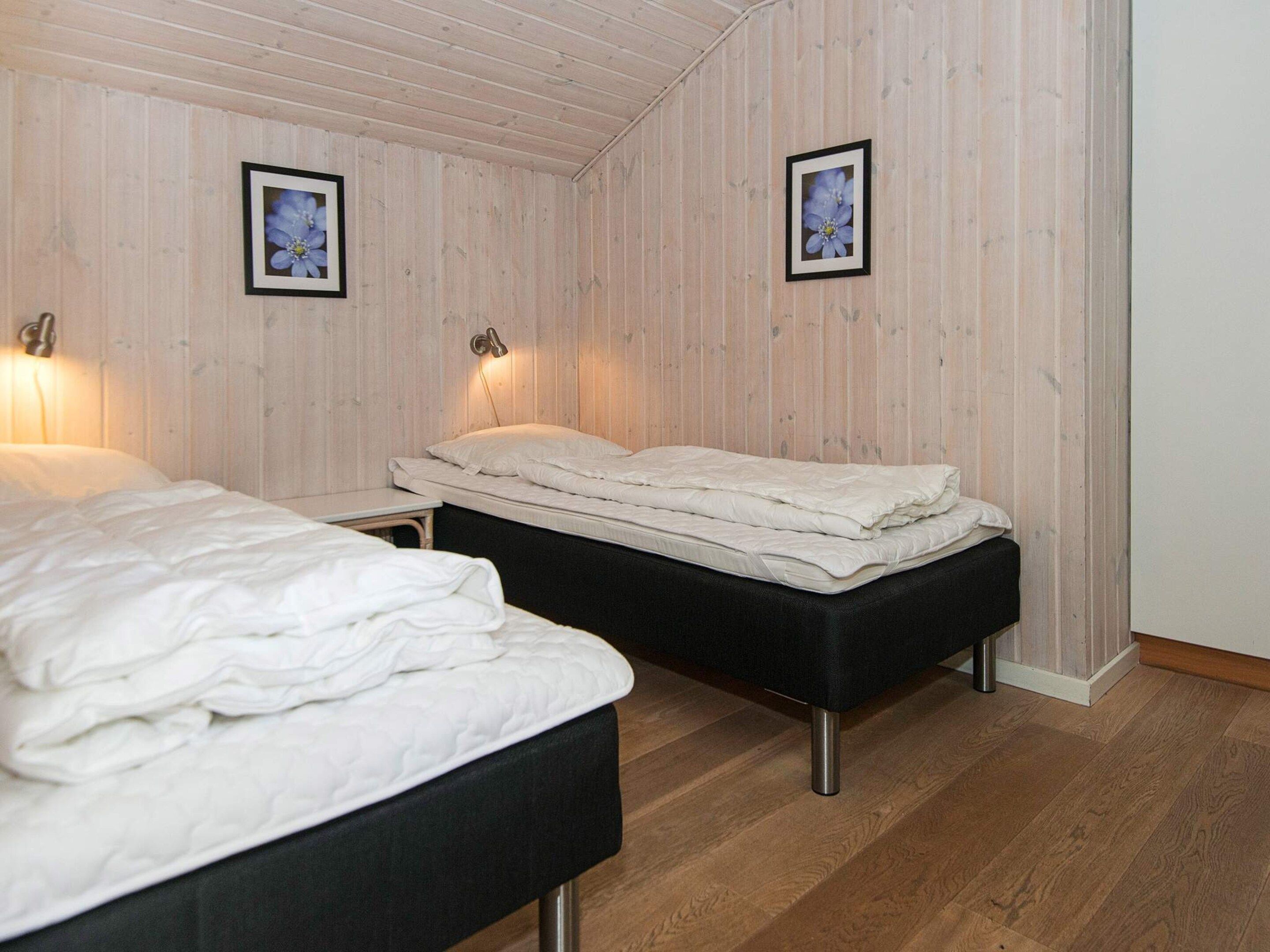 Habitación con dos camas, paredes de madera y cuadros enmarcados.