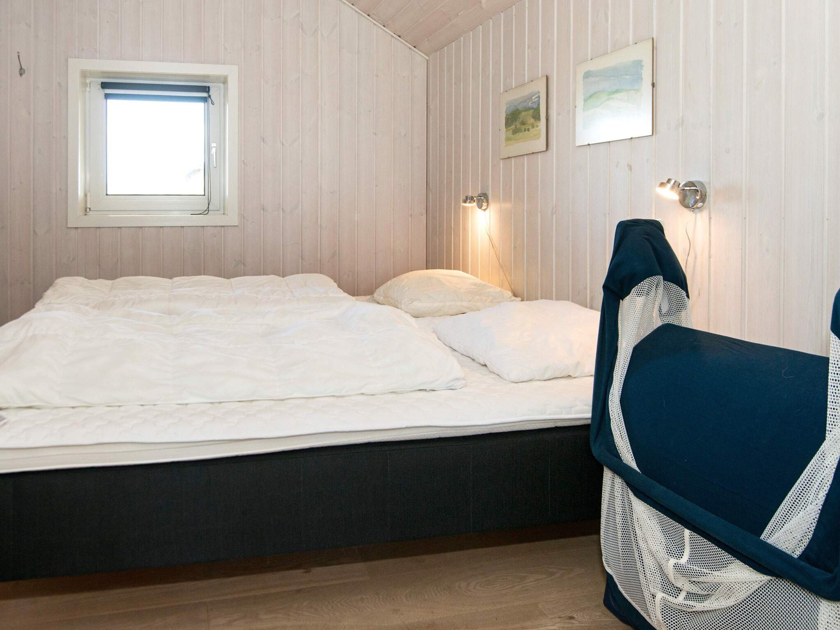 A bedroom with a bed, a window, and two wall-mounted lights.