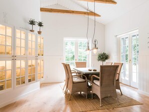 Een eetgedeelte met rieten stoelen, een tafel en hangende hanglampen.