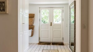 A hallway with white doors, a tiled floor, and a large mirror on the right. - 5 Star Holiday Home in Henne (Henne)