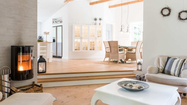 A modern living room with a fireplace, a dining area, and a kitchen visible through an open door. - 5 Star Holiday Home in Henne (Henne)
