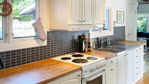 Une cuisine dotée d’un plan de travail en bois, de meubles blancs, d’une cuisinière et d’un revêtement mural en carreaux.