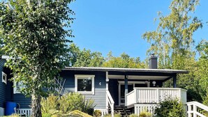 Une maison à deux étages avec un porche, une cheminée et une petite terrasse.