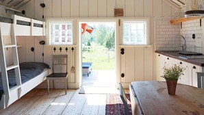 A cozy, compact room with a loft bed, a small table, and a kitchen area with a sink and window. - 5 Person Holiday Home in Mellosa (Flen)